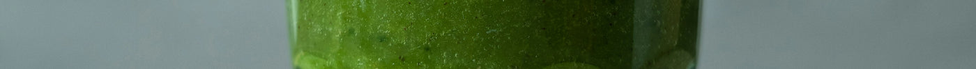 Green moringa smoothie in a glass with a straw