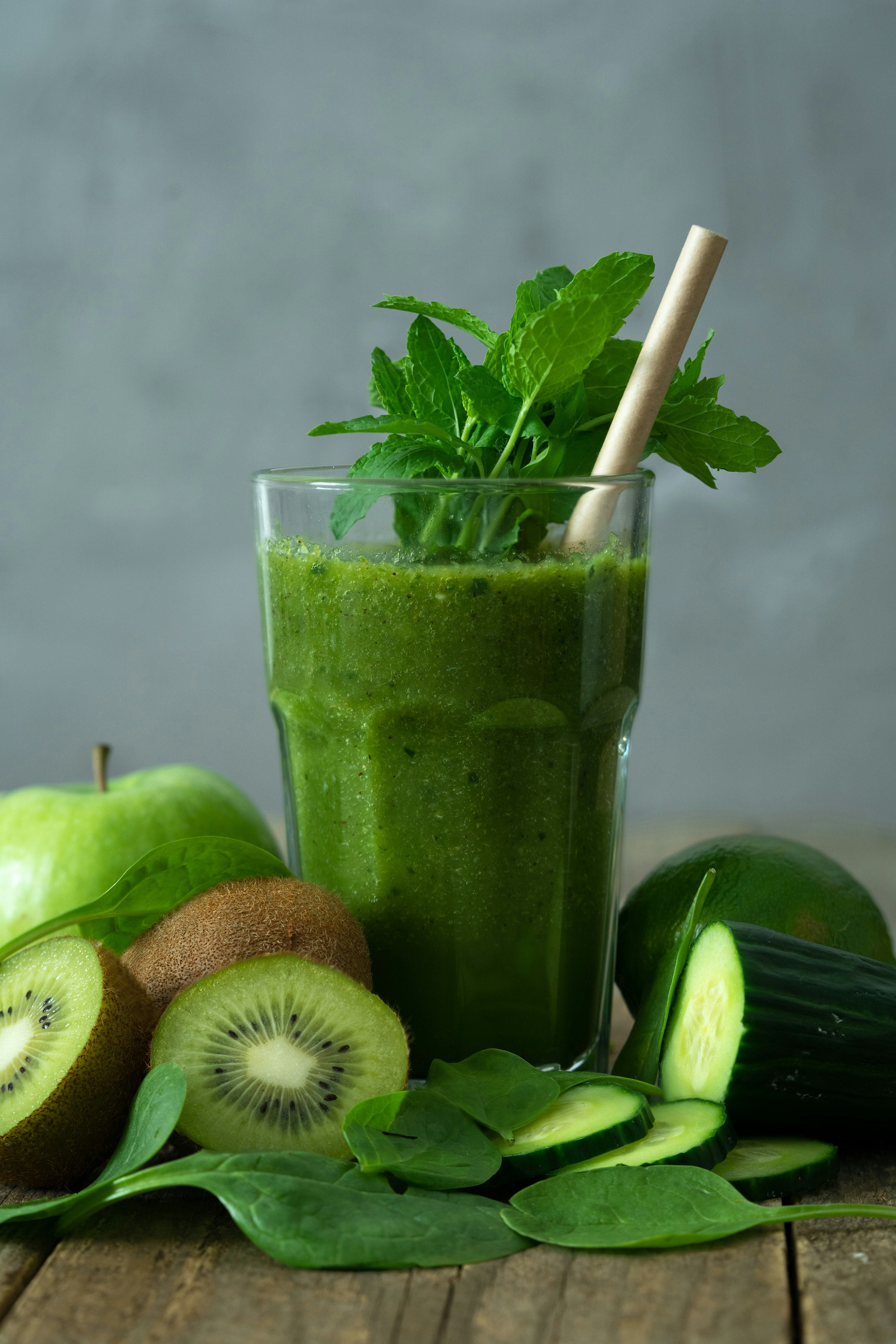 Green moringa smoothie in a glass with a straw